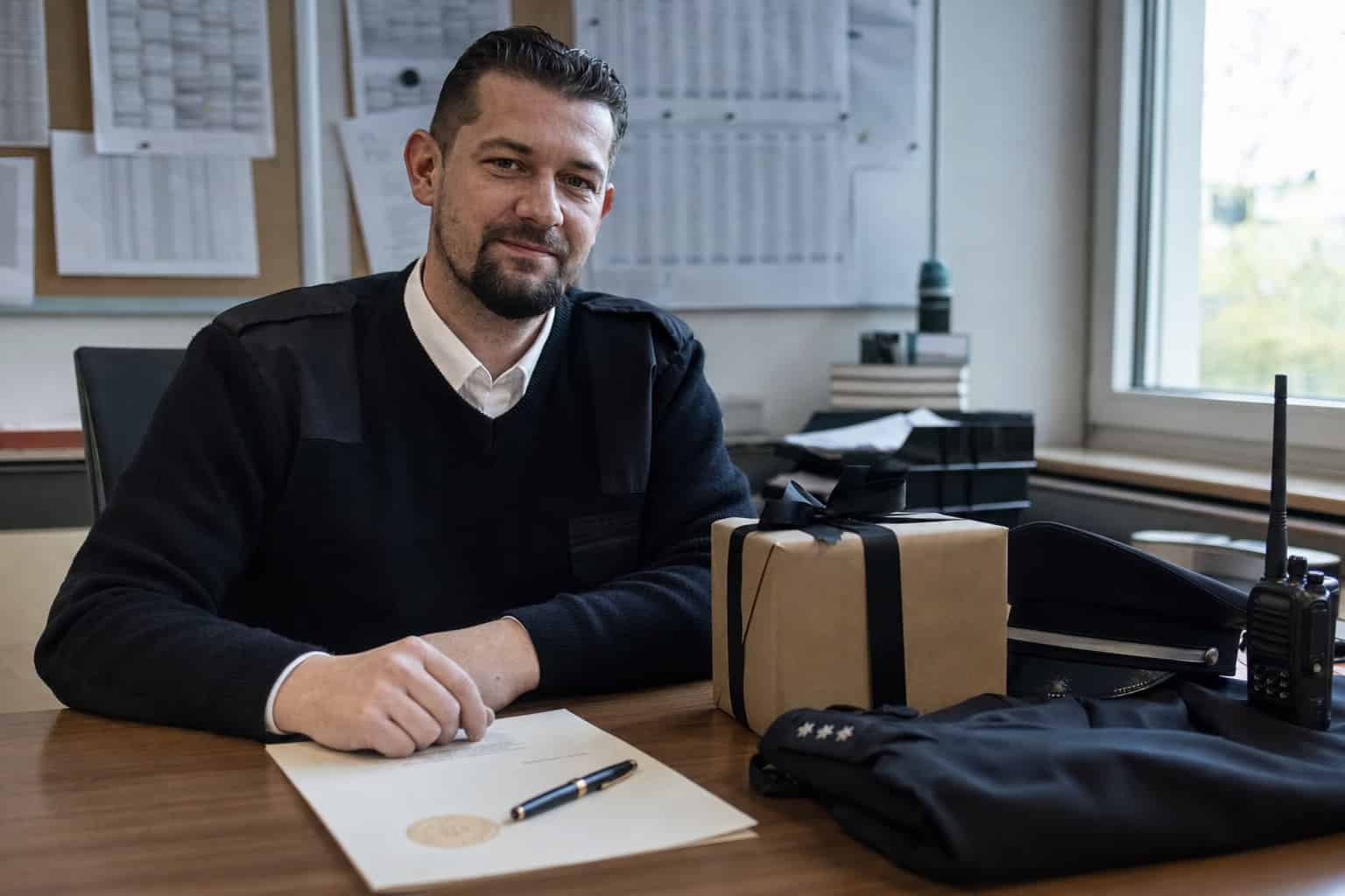 Sicherheitsmitarbeiter am Schreibtisch neben einem verpackten Geschenk